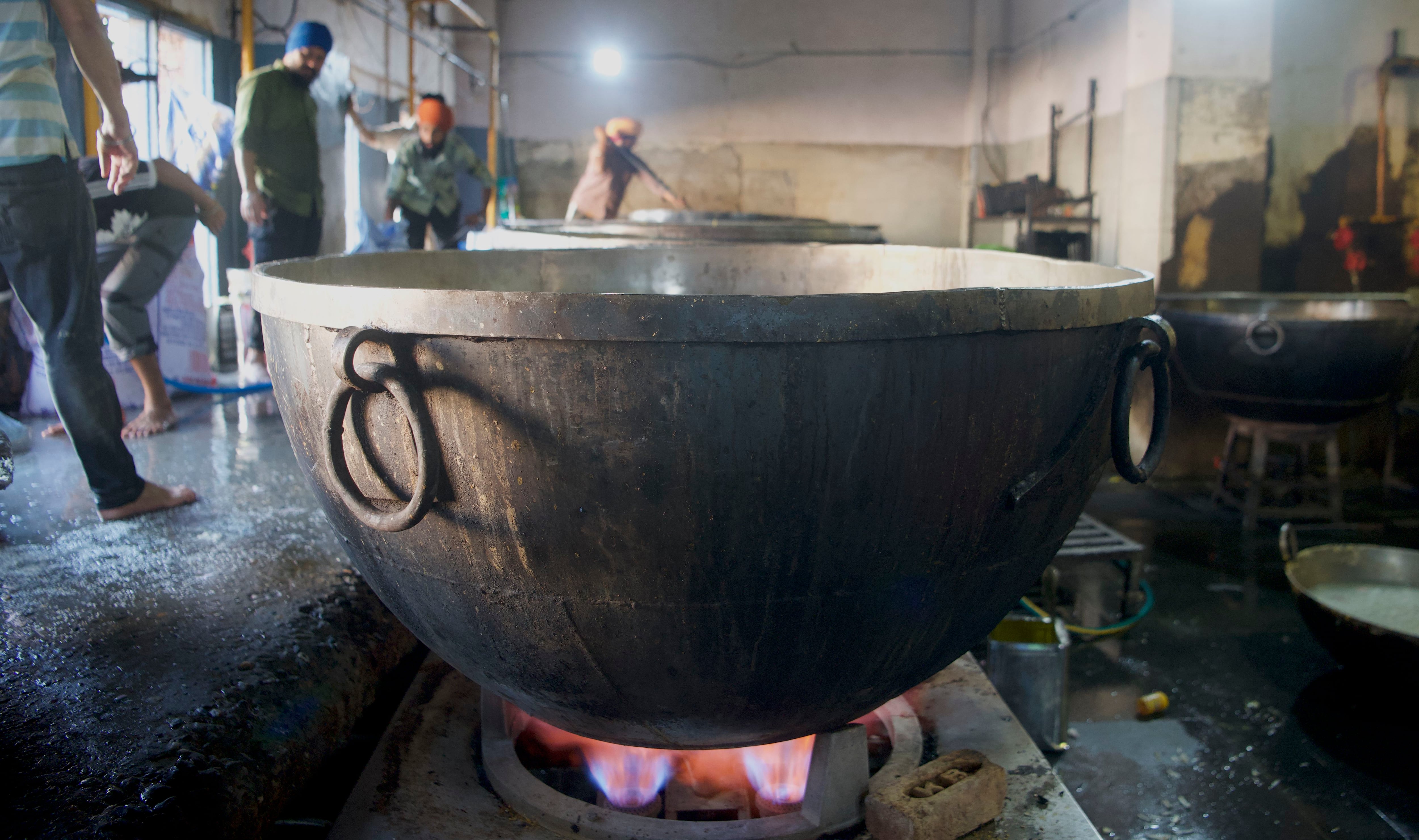A cook in the Golden Temple cooks in an extremely large pot.